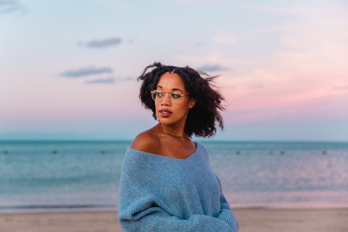 Lauren Ash at the lakeshore at dusk in a blue sweater.